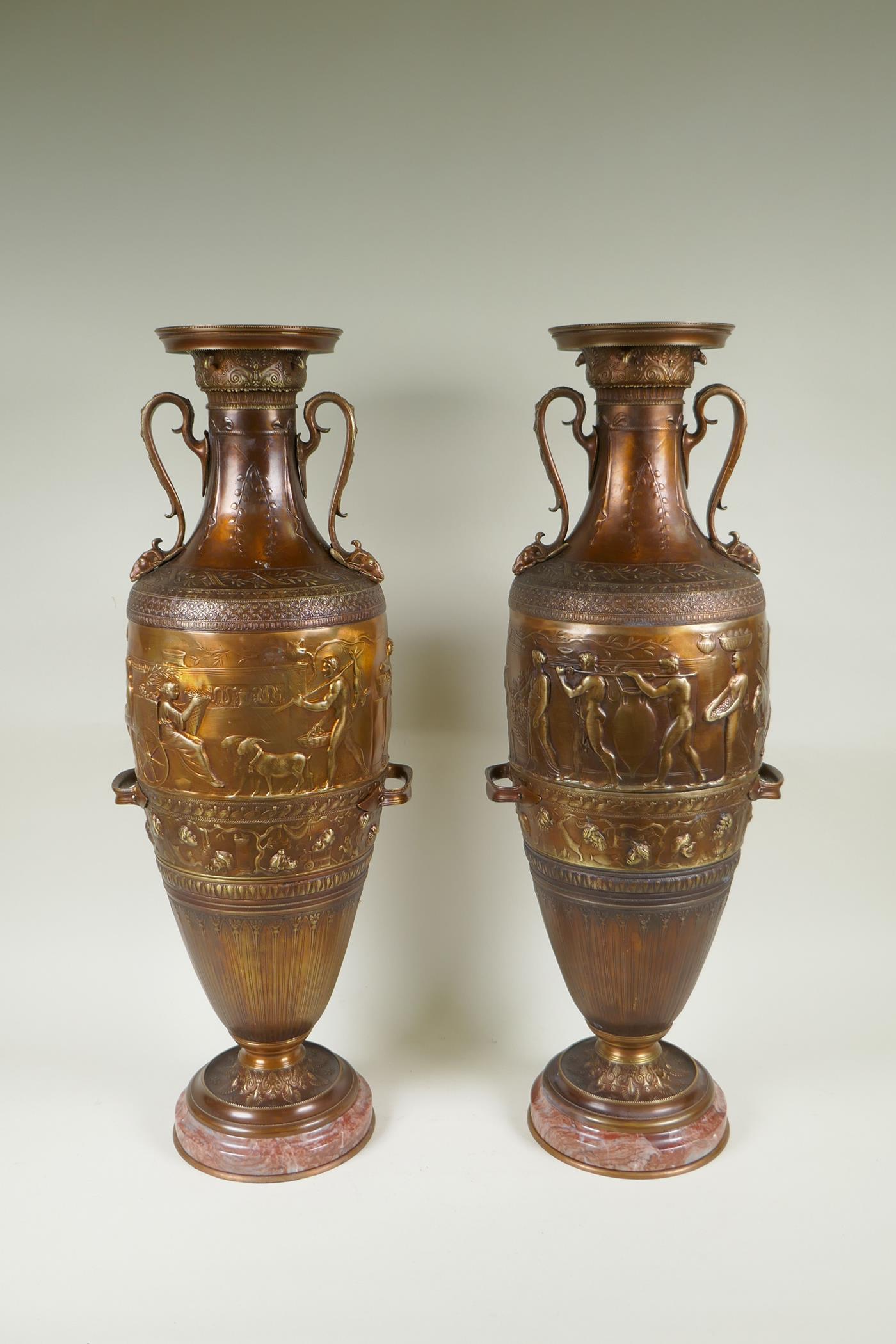 After Barbedienne, a pair of bronze Grand Tour style urns with two handles and raised figural