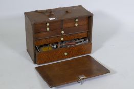An antique mahogany tool chest containing vintage engineer's tools