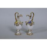 A pair of Continental hard paste porcelain ewers with fine applied floral decoration and gilded