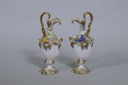 A pair of Continental hard paste porcelain ewers with fine applied floral decoration and gilded
