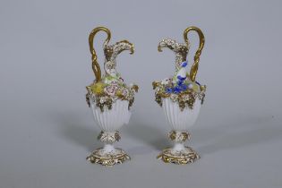 A pair of Continental hard paste porcelain ewers with fine applied floral decoration and gilded