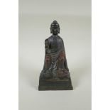 A Chinese bronze Buddha seated on a throne, with the remnants of gilt and copper patina, 23cm high