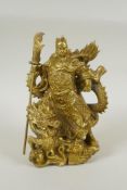 A Chinese gilt bronzed metal figure of Guan Yin standing on the back of a dragon, 22cm high