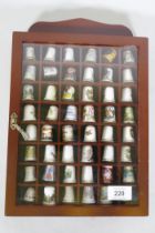 A collection of 48 porcelain thimbles in a display case, 32 x 22 x 4cm