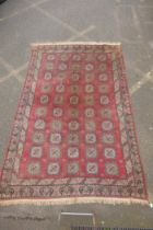 A hand woven Caucasian carpet with a bespoke all over Bokharra design on a salmon pink ground, 185 x