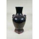 A Chinese treacle glazed porcelain vase with two mask handles, YongZheng mark to base, on a hardwood
