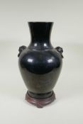A Chinese treacle glazed porcelain vase with two mask handles, YongZheng mark to base, on a hardwood