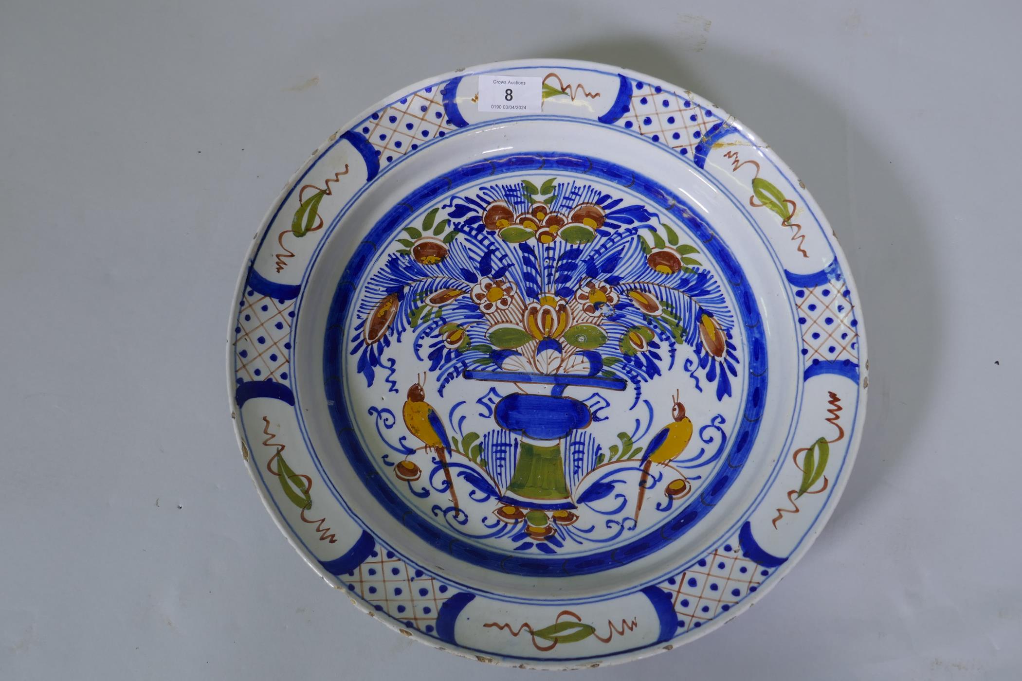 A Delft pottery charger with polychrome decoration of a vase and two birds, marked to base, Dutch