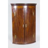 A Georgian mahogany bow fronted hanging corner cupboard, with inlaid decoration, H hinges and