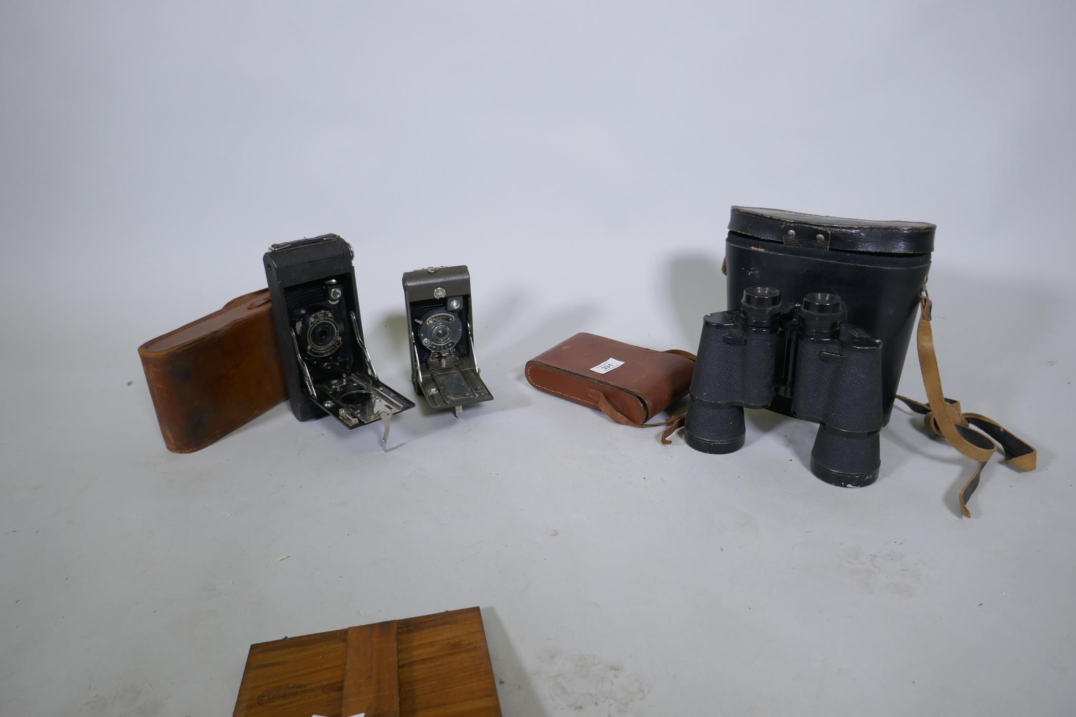 An Ensign Greyhound folding camera, Kodak No1A pocket camera and a pair of Greenkat field glasses