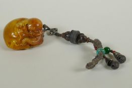 A Chinese reconstituted amber soapstone elephant and monkey pendant/toggle, 7cm long