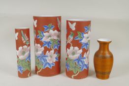 A graduated set of three Chinese iron red ground porcelain cylinder vases with floral decoration,