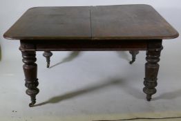 A Victorian mahogany pull out extending dining table raised on turned supports with carved