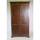 A late C19th/early C20th mahogany two door wardrobe/cupboard, with panelled doors, raised on bracket