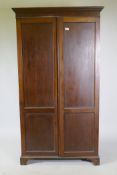 A late C19th/early C20th mahogany two door wardrobe/cupboard, with panelled doors, raised on bracket