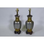 A pair of white metal table lamps with brass Oriental style lotus leaf decoration, on wood bases,