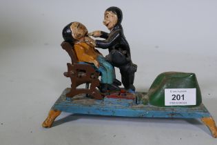 A painted cast iron money box in the form of a dentist, 22cm long, 16cm high