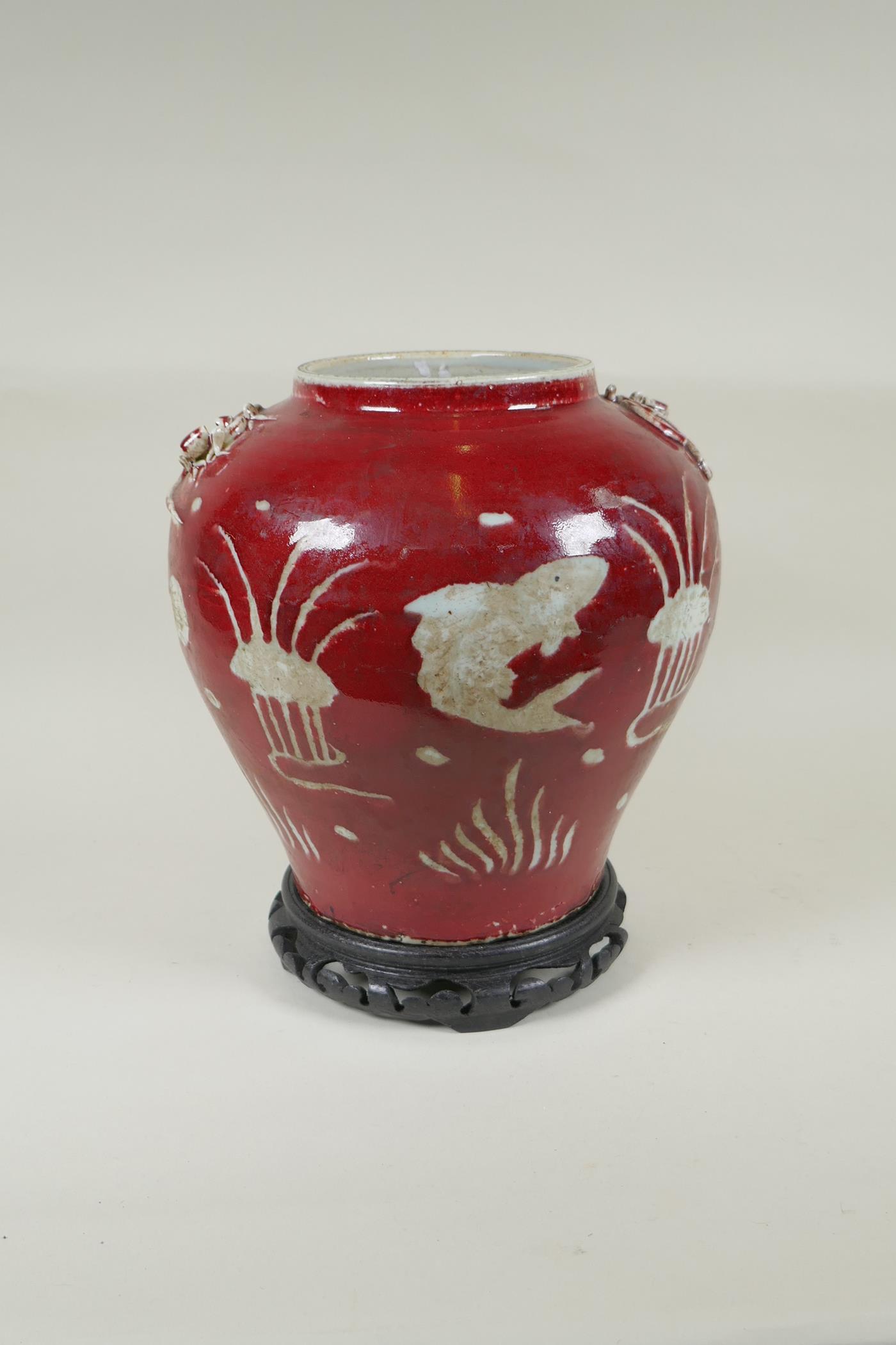 A Chinese red and white porcelain baluster vase, decorated with carp in a lotus pond, on a carved