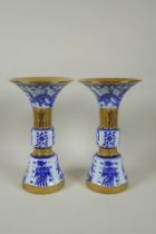 A pair of Chinese blue and white gu shaped vases with banded gilt highlights, and decorated with