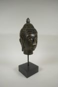A gilt composition Buddha head on a display stand, 35cm high