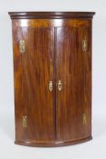 A Georgian mahogany bow fronted hanging corner cupboard, with inlaid decoration, H hinges and