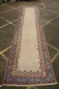 An Oriental cream ground hand woven wool runner with blue border and floral designs, 150 x 600cm