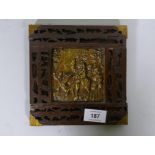 An antique Folk Art wood panel with fret borders and metal mounts, the brass plaque with repousse