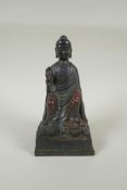 A Chinese bronze Buddha seated on a throne, with the remnants of gilt and copper patina, 23cm high