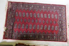 A Bokhara hand woven wool rug, red ground with traditional pattern, 7 x 157cm