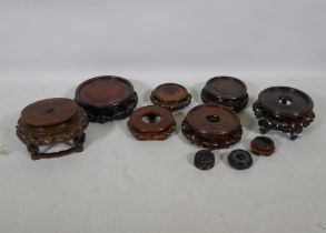 Nine Chinese hardwood vase stands with carved lotus decoration, and a carved jar cover