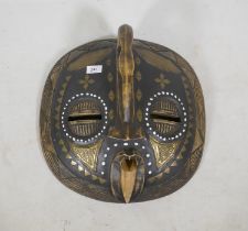 An African tribal mask, inlaid with brass and shells, 43cm diameter