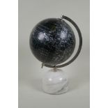 A black terrestrial globe on a reconstituted marble base, produced in India, 33cm high