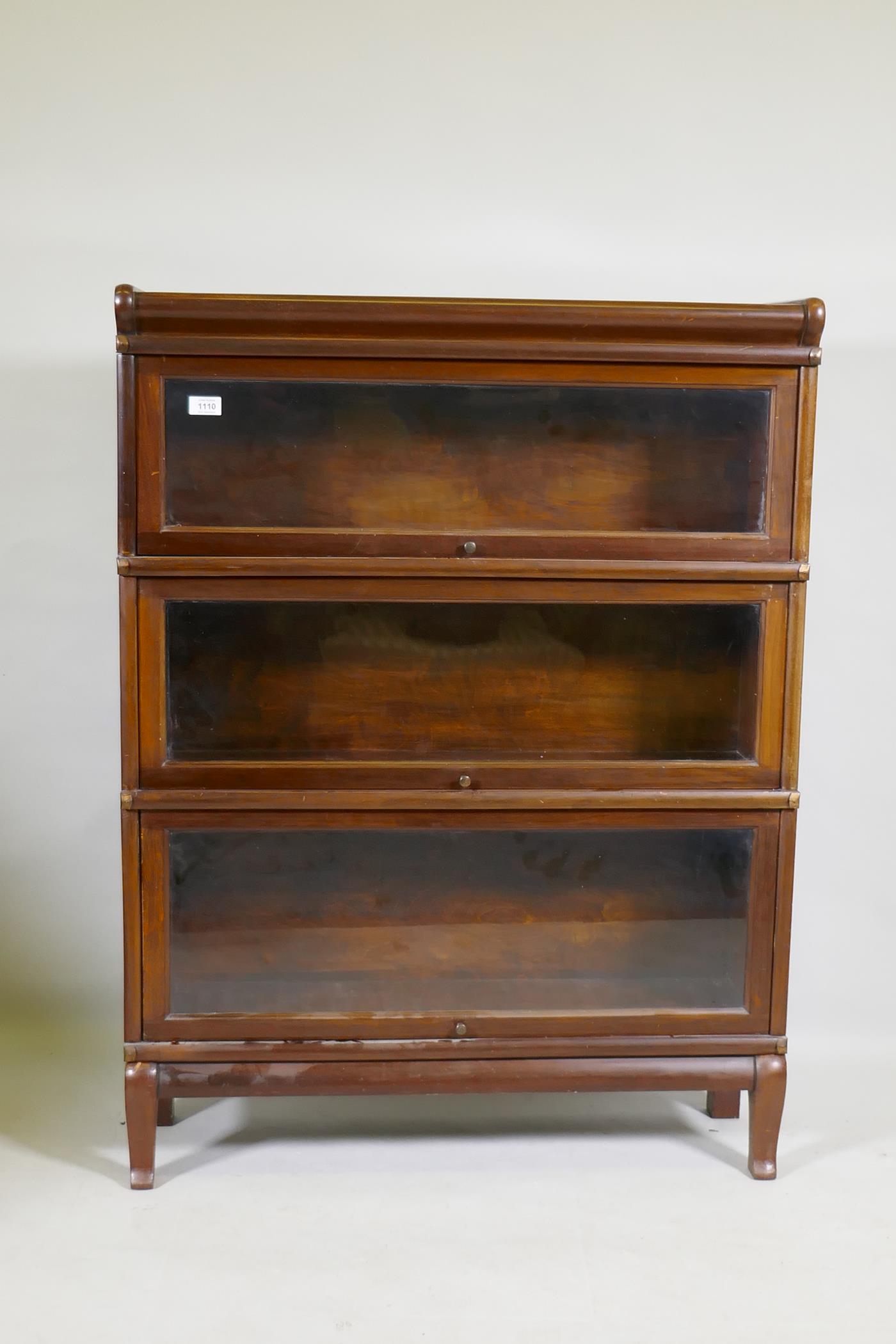 A mahogany Globe Wernicke style three section bookcase, raised on a base with shaped supports, 87