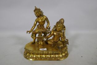An Oriental gilt bronze figure group, Buddha accompanied by a female musician, 29cm high