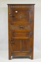 A mid century oak hall cupboard with panelled sides and doors and carved decoration, two cupboards