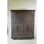 An early C18th two door cupboard with fielded panel doors and panelled sides, raised on a plinth