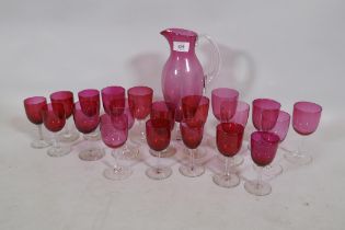 A quantity of matched cranberry coloured drinking glasses and a carafe, 27cm high