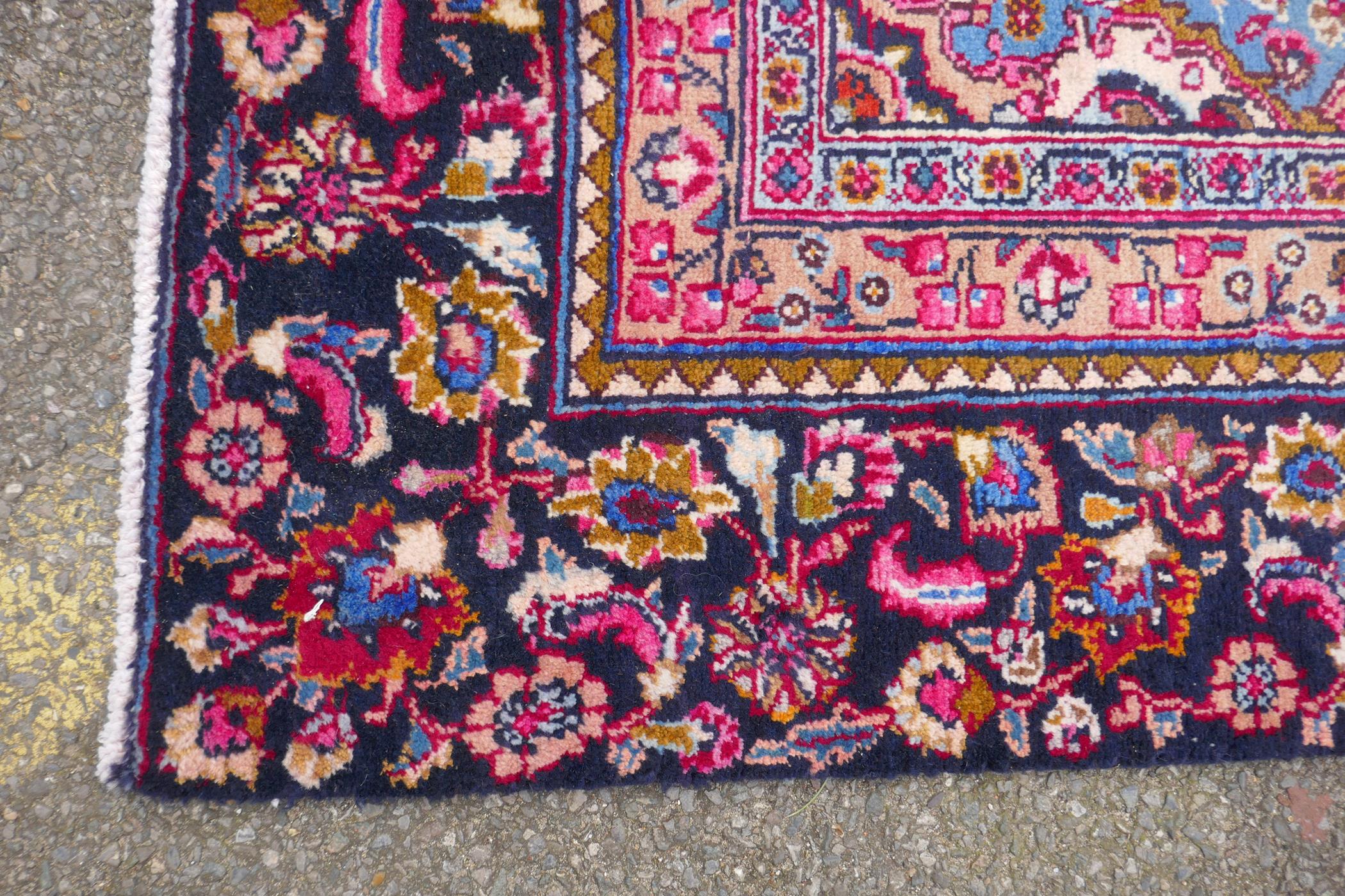 A claret and blue ground Persian Mashad carpet with a traditional floral medallion design, - Image 5 of 6