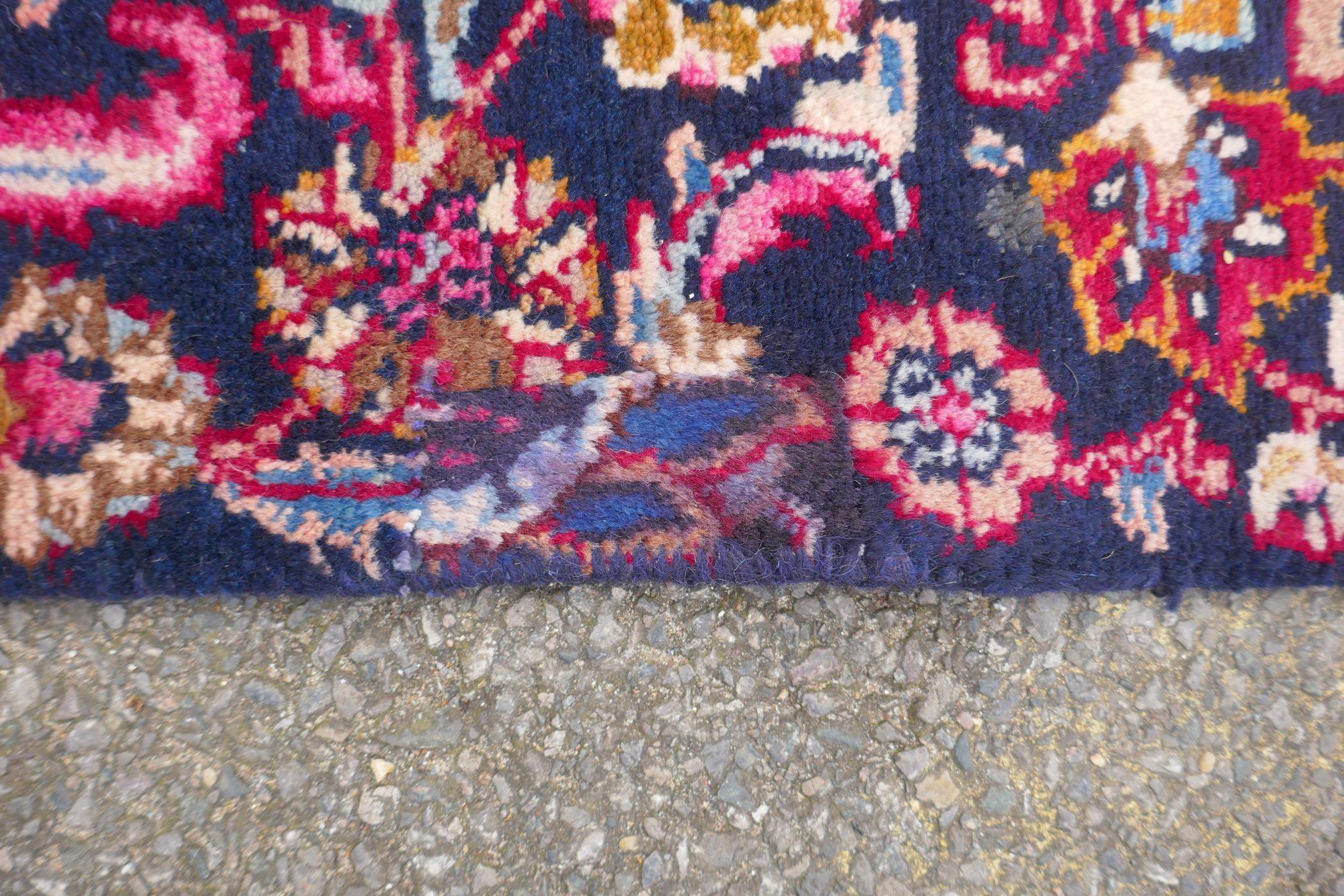 A claret and blue ground Persian Mashad carpet with a traditional floral medallion design, - Image 3 of 6