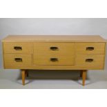 A mid century faded sapele six drawer chest with brass handles, raised on square tapering