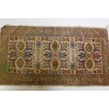 An antique hand woven Oriental rug with geometric designs n a buff coloured field, 68 x 125cm