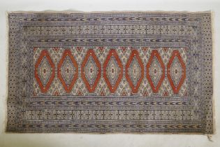 A Persian wool rug with a triple diamond medallion design on a terracotta field with beige