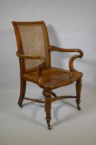 An early C19th Irish walnut elbow chair with bergere caned back, shepherd's crook arms and saddle