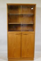 A mid century teak cabinet, with sliding glass doors over two cupboards, 69 x 36 x 144cm