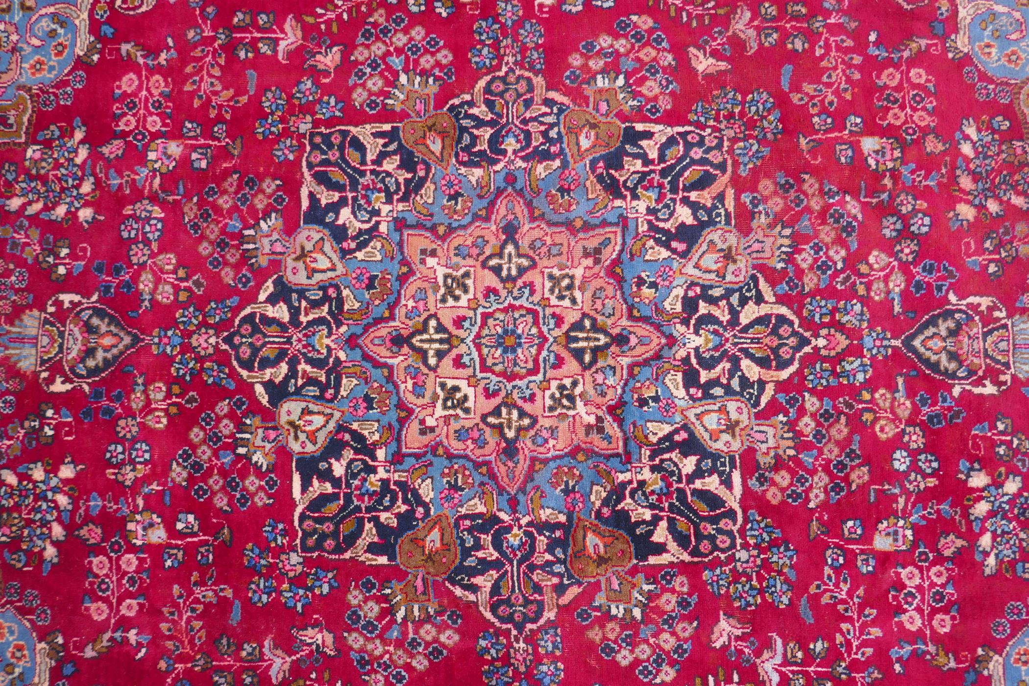A claret and blue ground Persian Mashad carpet with a traditional floral medallion design, - Image 4 of 6