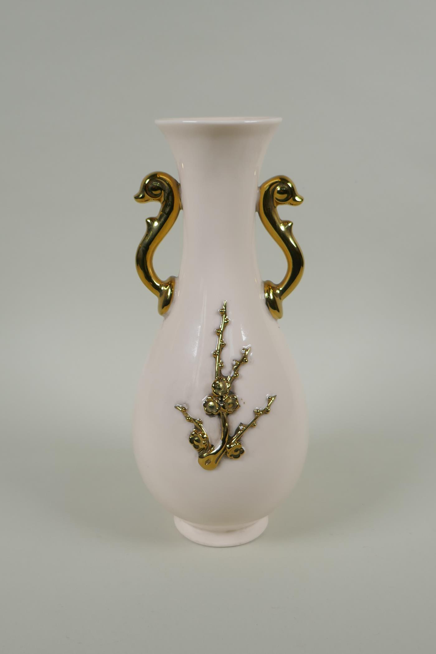 A Chinese cream glazed porcelain pear shaped vase with two gilt handles and raised prunus