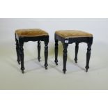 A pair of Victorian ebonised stools, with shaped friezes, raised on turned supports with metal