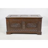 An oak coffer, the top with three fielded panels, the front with  carved frieze and double panel,