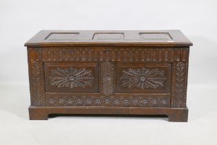 An oak coffer, the top with three fielded panels, the front with  carved frieze and double panel,