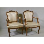 A pair of C19th French carved beechwood open armchairs with shaped backs, raised on cabriole